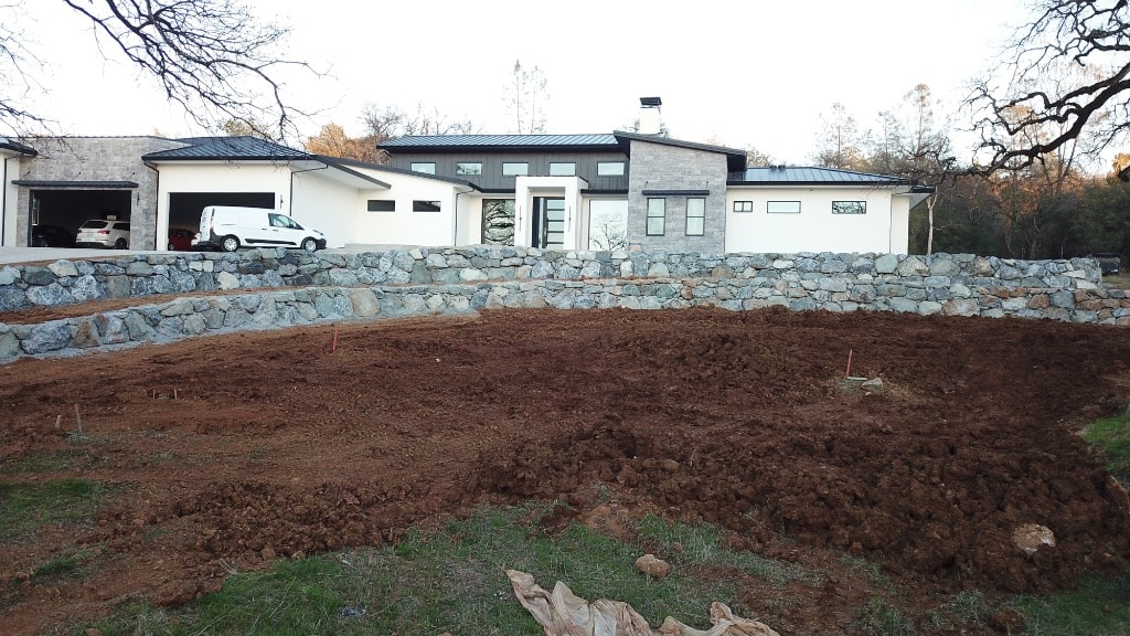 Modern home with stone retaining wall and graded landscape